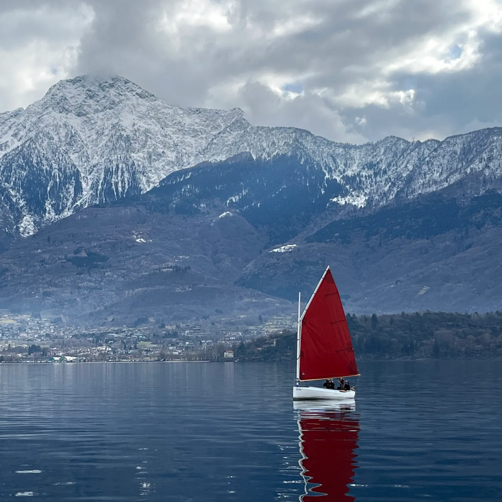 Una vela rossa sul Lago di Como davanti alle montagne